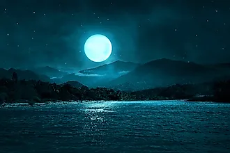 Lake landscape under a starry night sky with full moon
